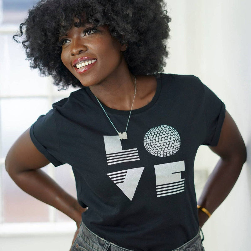 Woman wearing a black t-shirt with a graphic design, standing indoors.