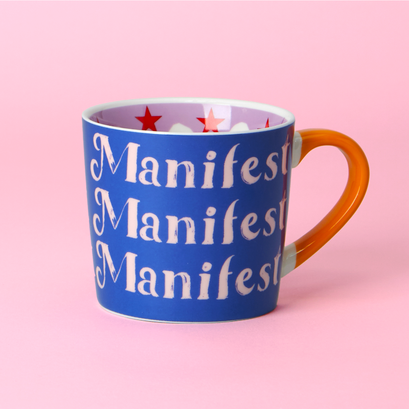 Blue mug with 'Manifest' text on a pink background
