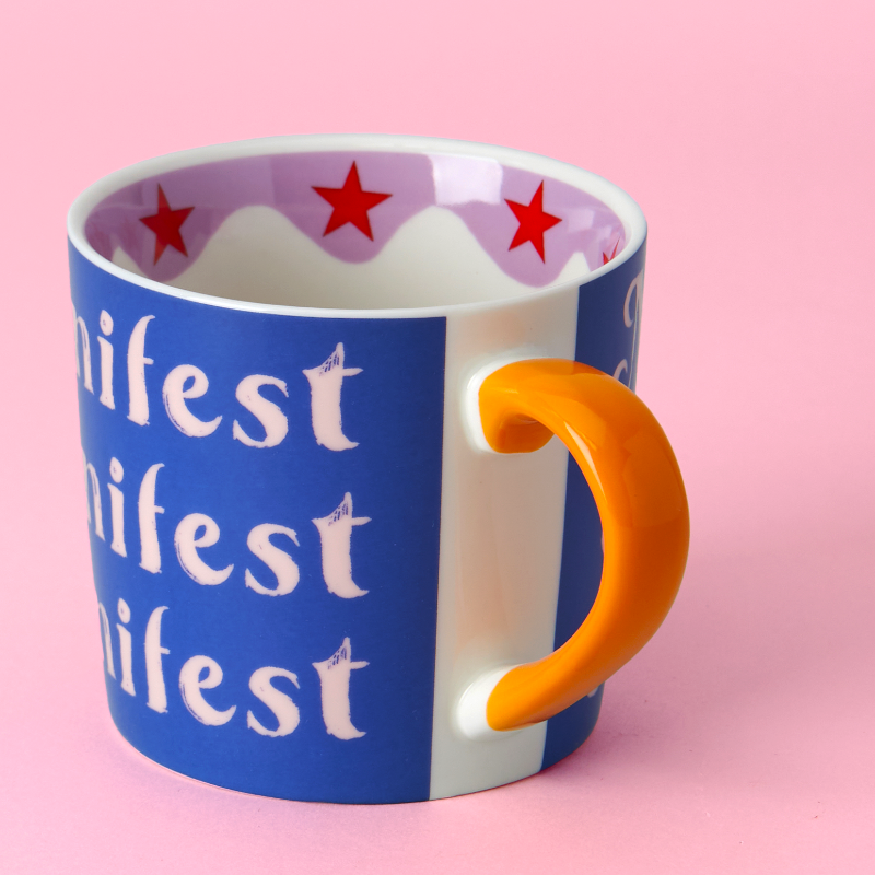 Blue mug with orange handle and red stars on a pink background