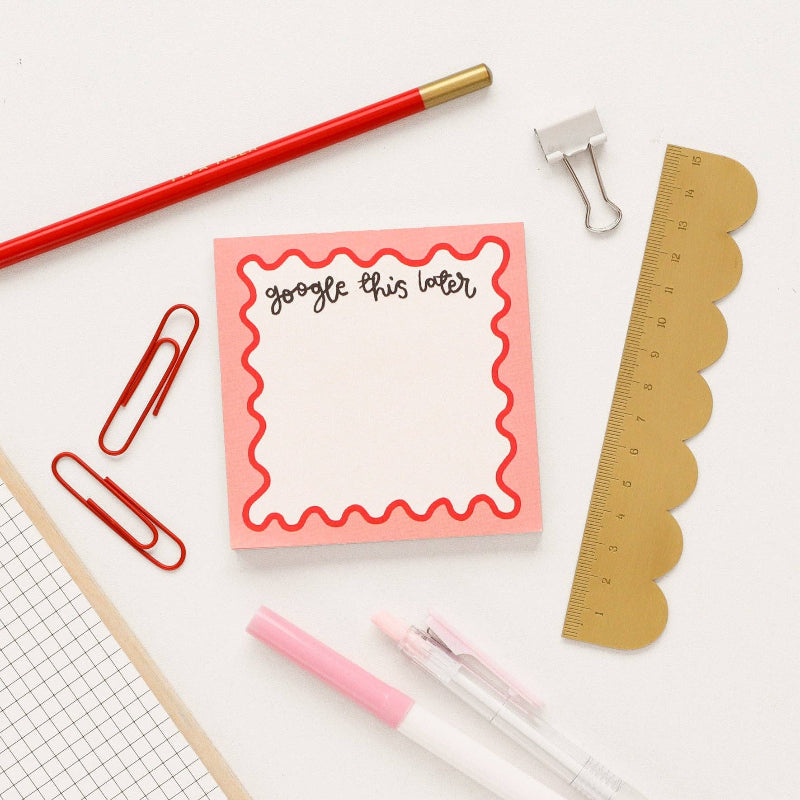 Note pad with 'google this later' text, ruler, markers, and paper clips on a white background