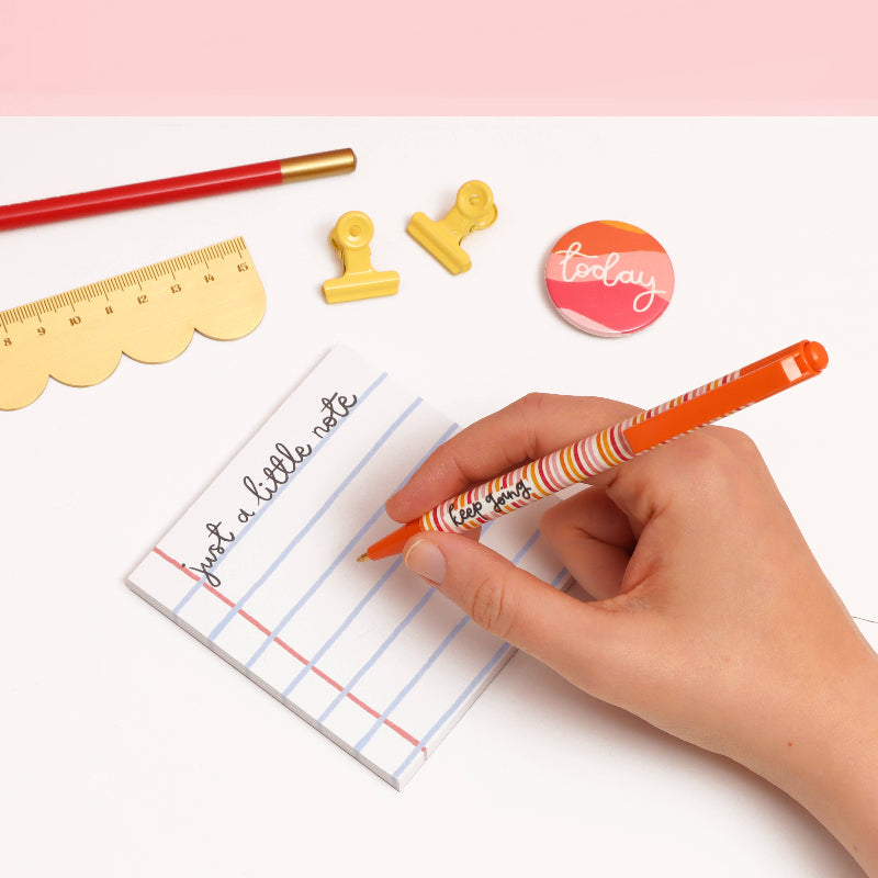 Hand writing on lined paper with stationery items on a white background