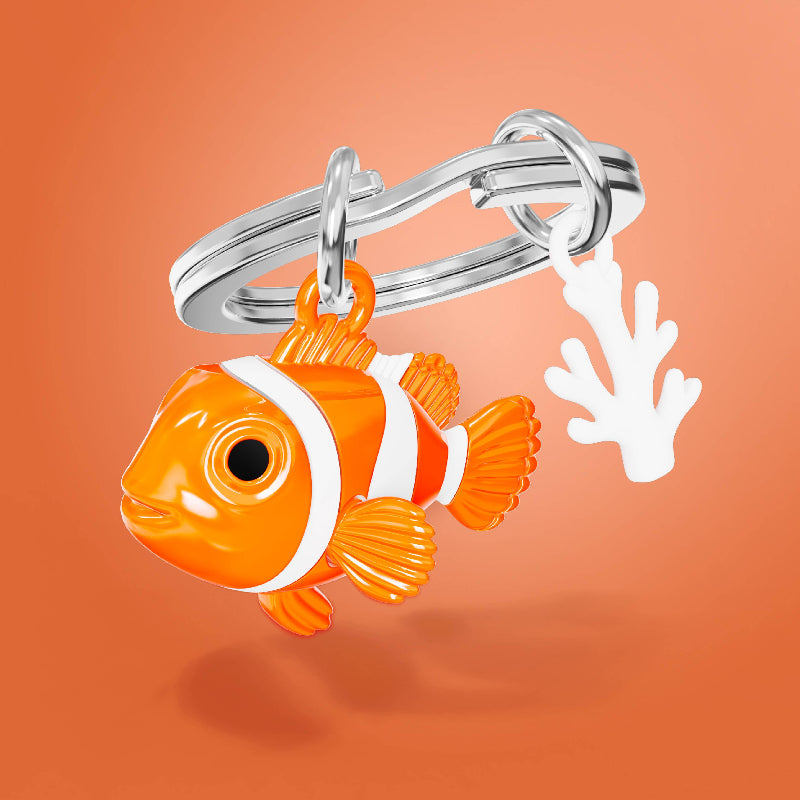 An orange and white clownfish keychain charm with a silver split ring and a small white coral accent, shown on a solid orange background.