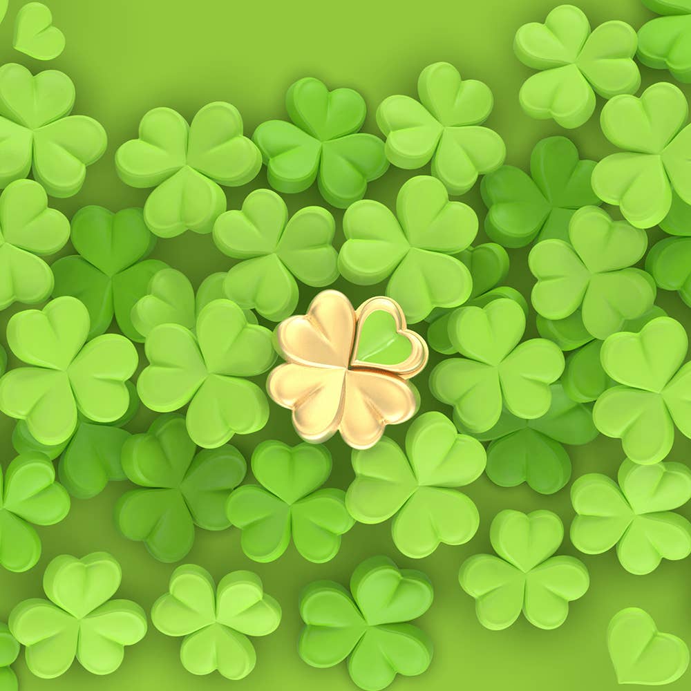 Gold four-leaf clover on a green background with additional four-leaf clovers