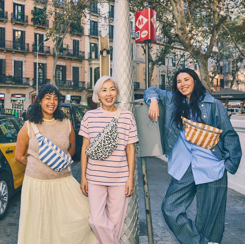 Three women standing wearing Roka Mill HIll Crossbody Bag Leopard Print together on a city street, smiling and posing for a photo.