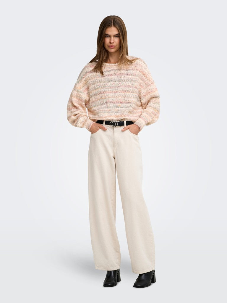 A woman modeling a light pink and cream textured knit sweater with wide-leg cream trousers, a black belt, and black boots, set against a plain light gray studio background.