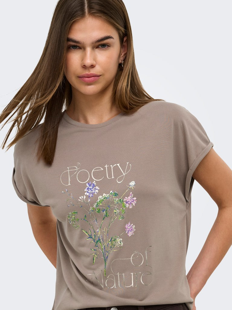 A woman wearing a taupe-brown short-sleeve t-shirt with a 'Poetry of Nature' graphic print featuring a watercolor flower illustration.