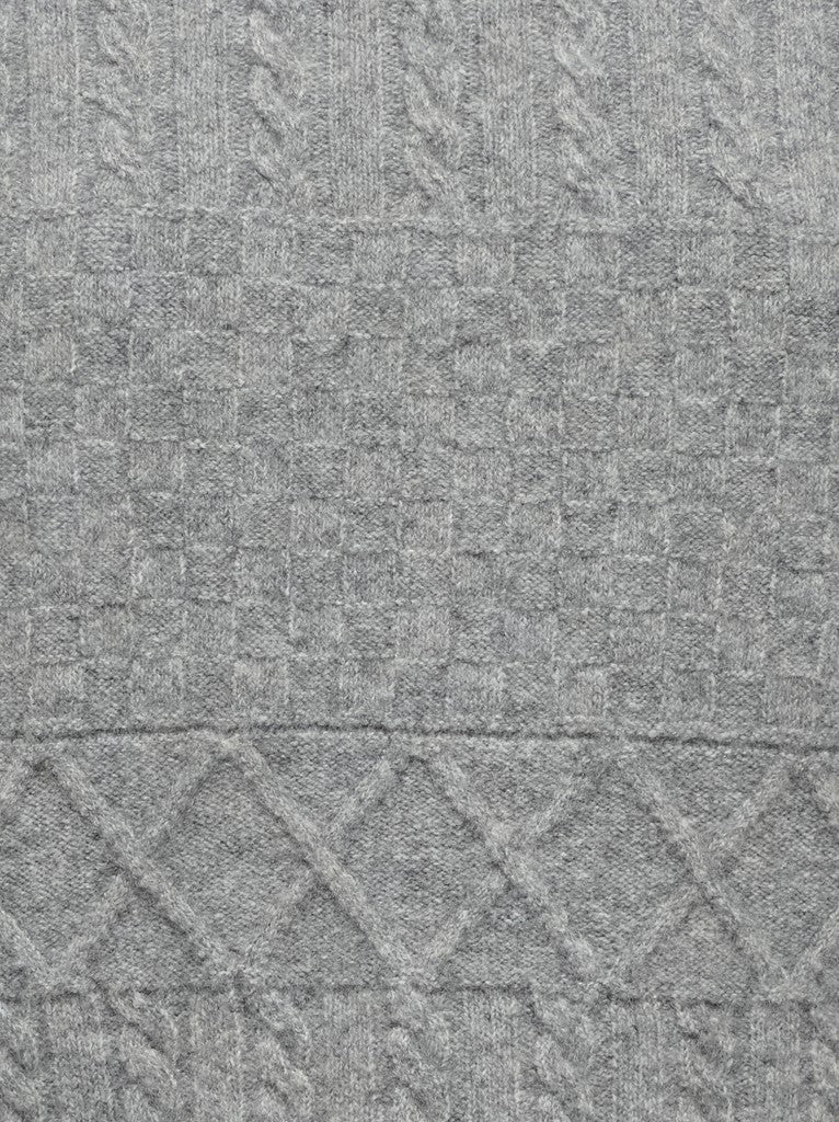 Close-up of a gray woven textile with a textured basketweave pattern and a decorative diamond border near the bottom.