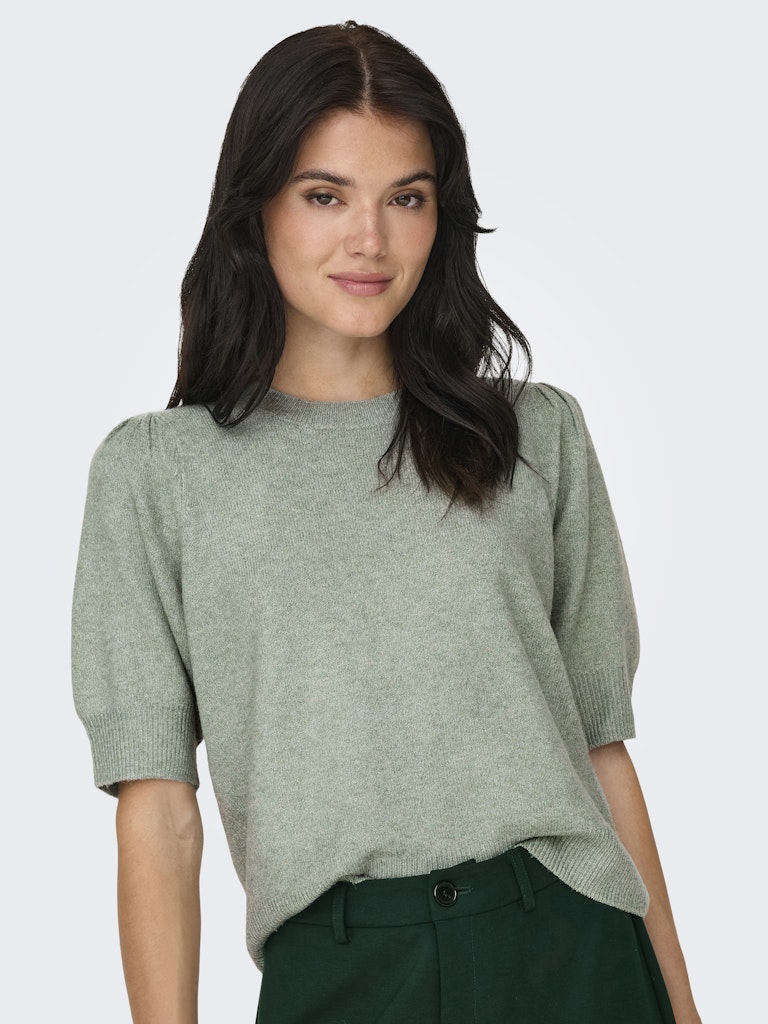 Woman wearing a light green sweater against a white background