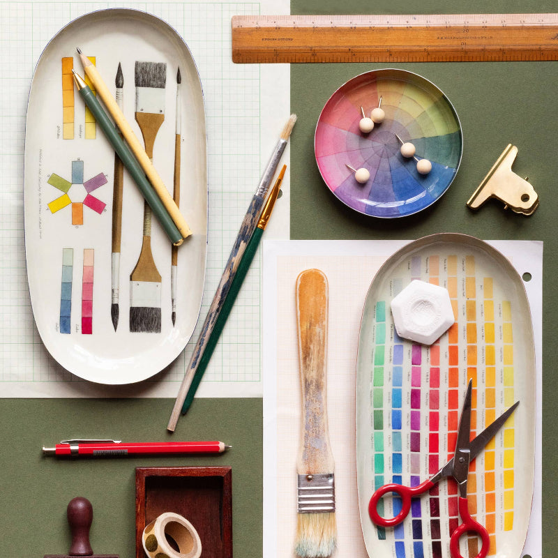 Art supplies including paintbrushes, pencils, and a ruler on a color swatch background.