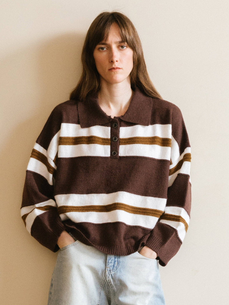 Person wearing a brown and white striped sweater against a beige wall
