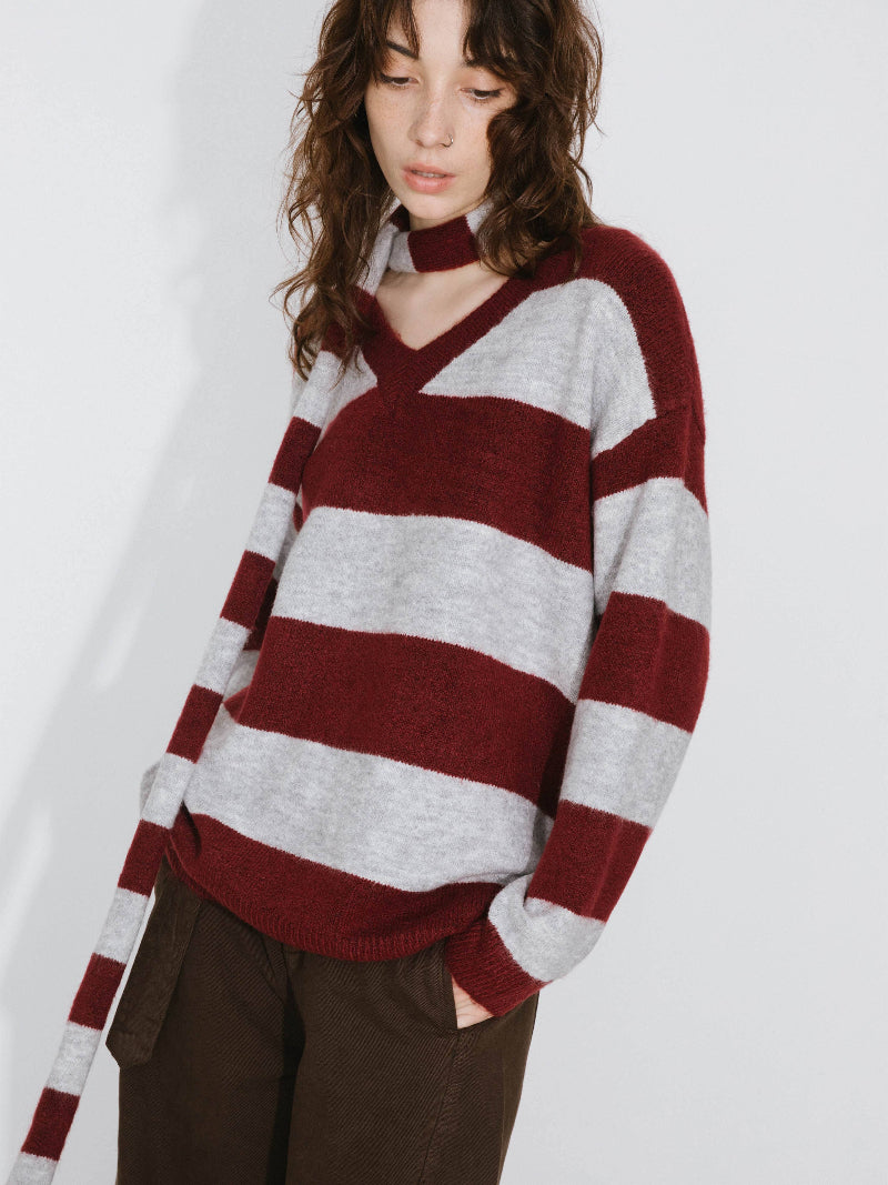 Person wearing a red and gray striped sweater on a white background
