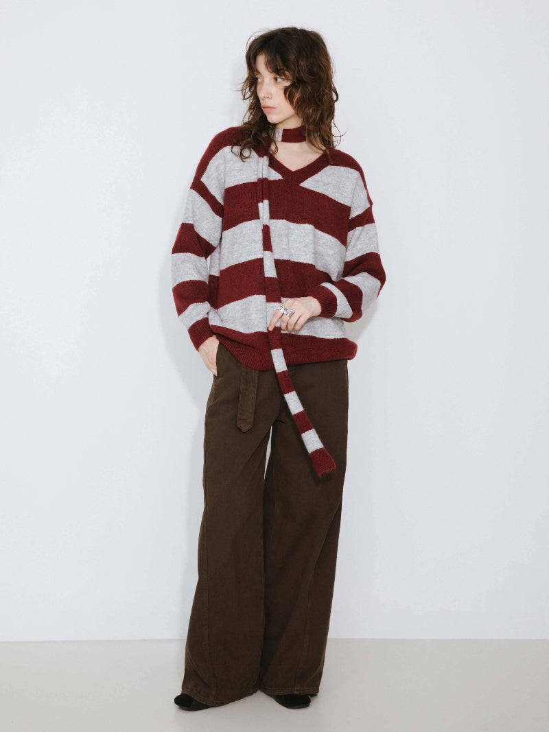 Person wearing a red and white striped sweater with brown pants on a white background
