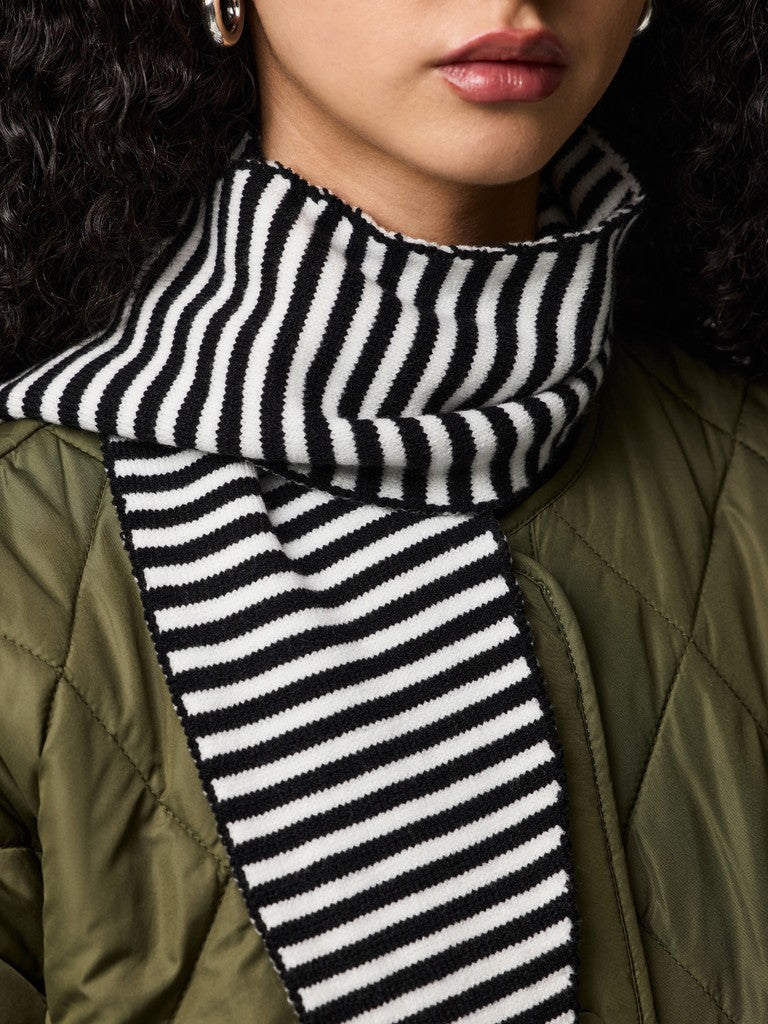 Person wearing a black and white striped scarf with a green jacket.