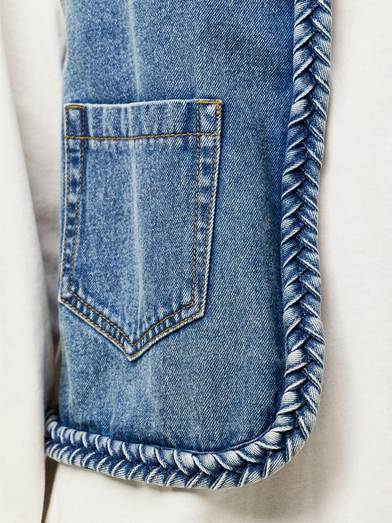 Close-up of a blue denim waistcoat with a pocket on a light background