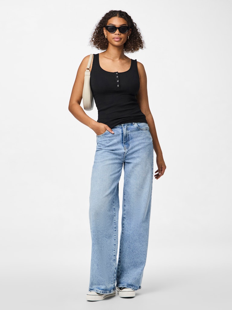 Woman wearing a black tank top and light blue jeans on a white background