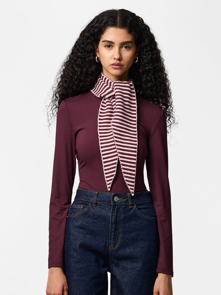 Woman wearing a maroon long-sleeve top with a striped scarf and blue jeans on a white background