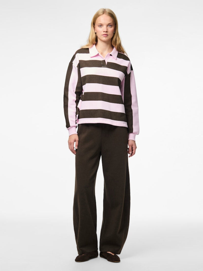 Person wearing a striped shirt and dark pants on a white background