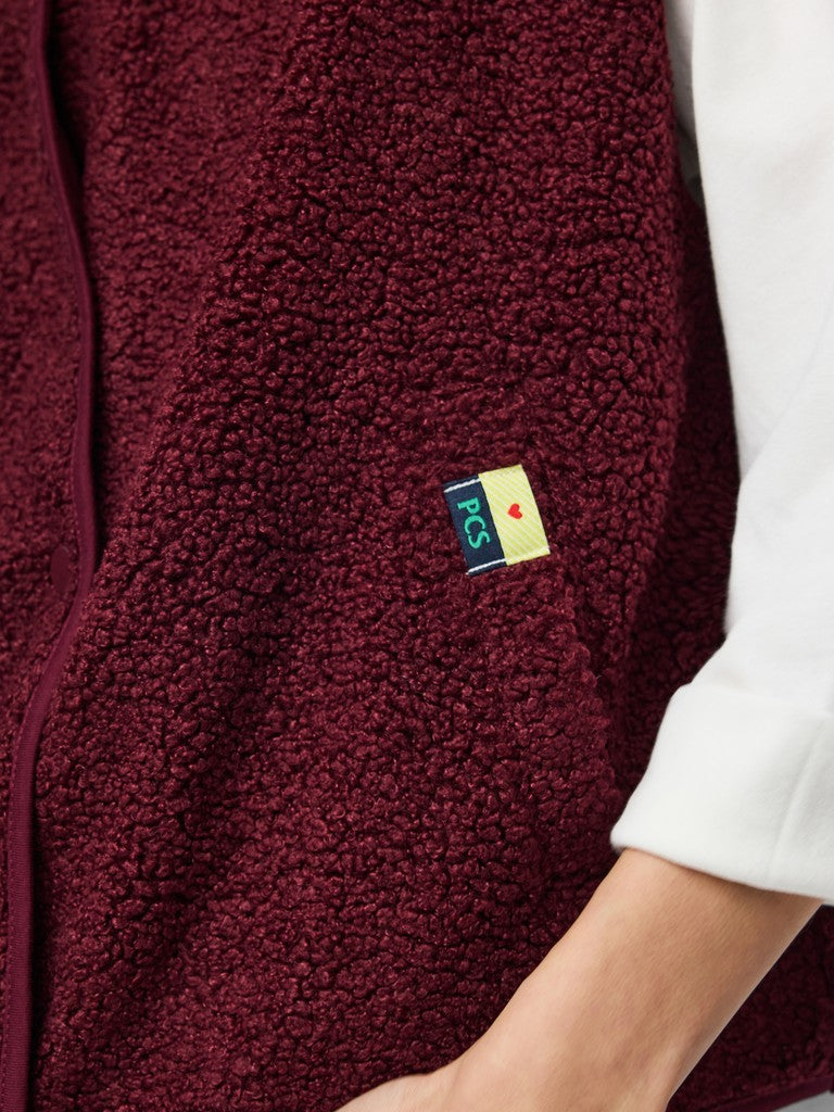 Close-up of a maroon fleece jacket with a brand logo on the chest.