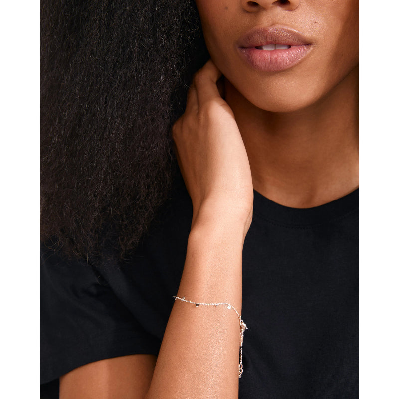 Woman wearing a delicate bracelet on her wrist with a plain background