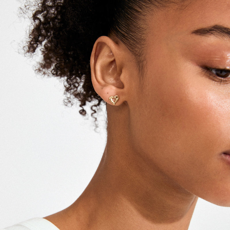 Close-up of a woman wearing a heart-shaped earring on a white background