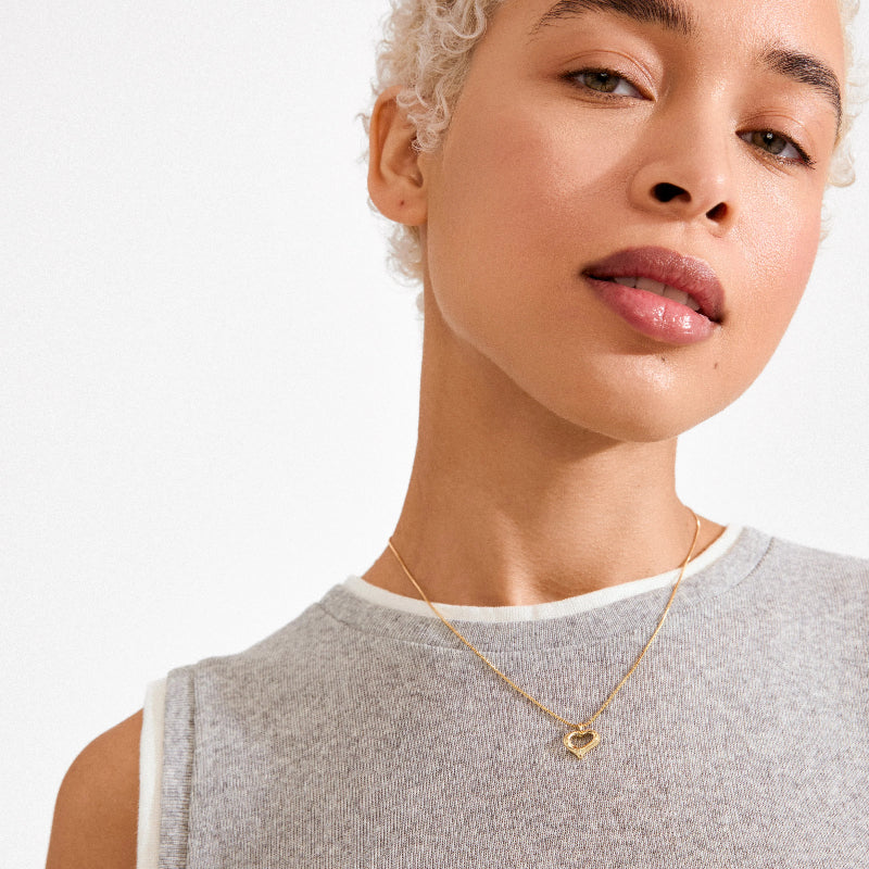 A woman wearing a gold necklace on a white background