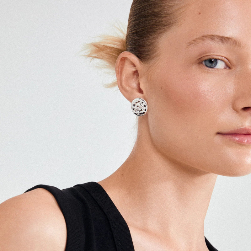 Close-up of a woman wearing a floral earring against a plain background