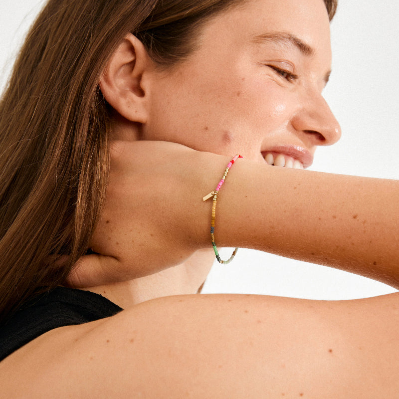 Woman wearing a colorful bracelet on her wrist with a neutral background