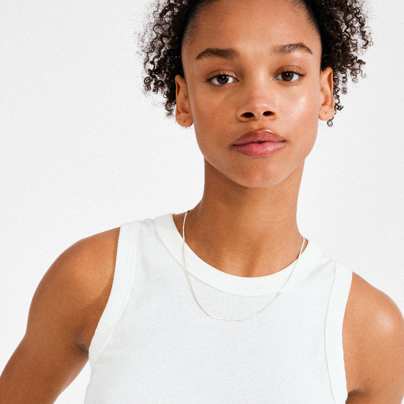 Person wearing a white tank top against a plain background