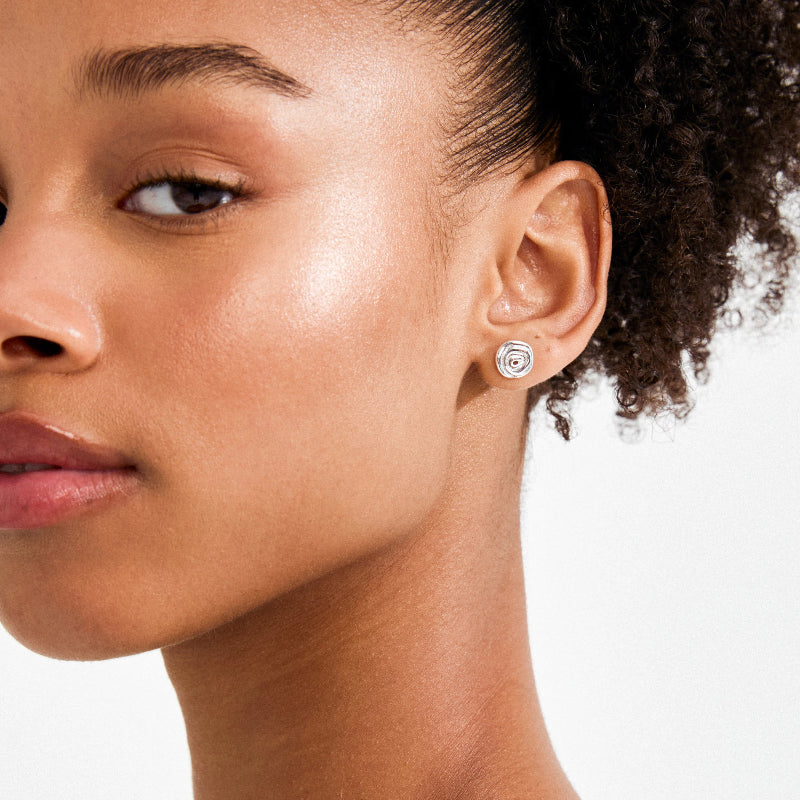 Close-up of a woman wearing a silver coloured earring on a white background