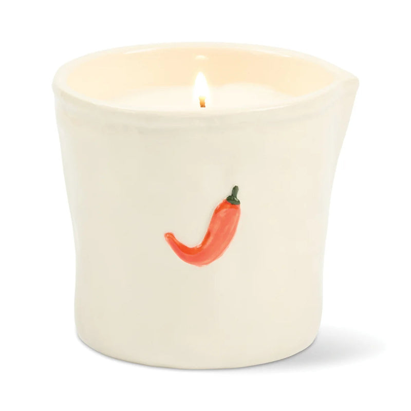 Candle in a white container with a red chili pepper design on a white background