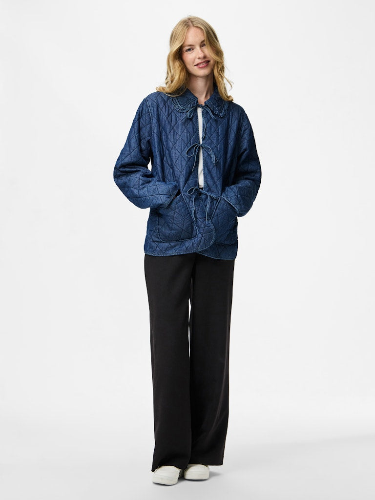 Woman wearing a Pieces Aura Short Quilt Jacket and black pants on a white background