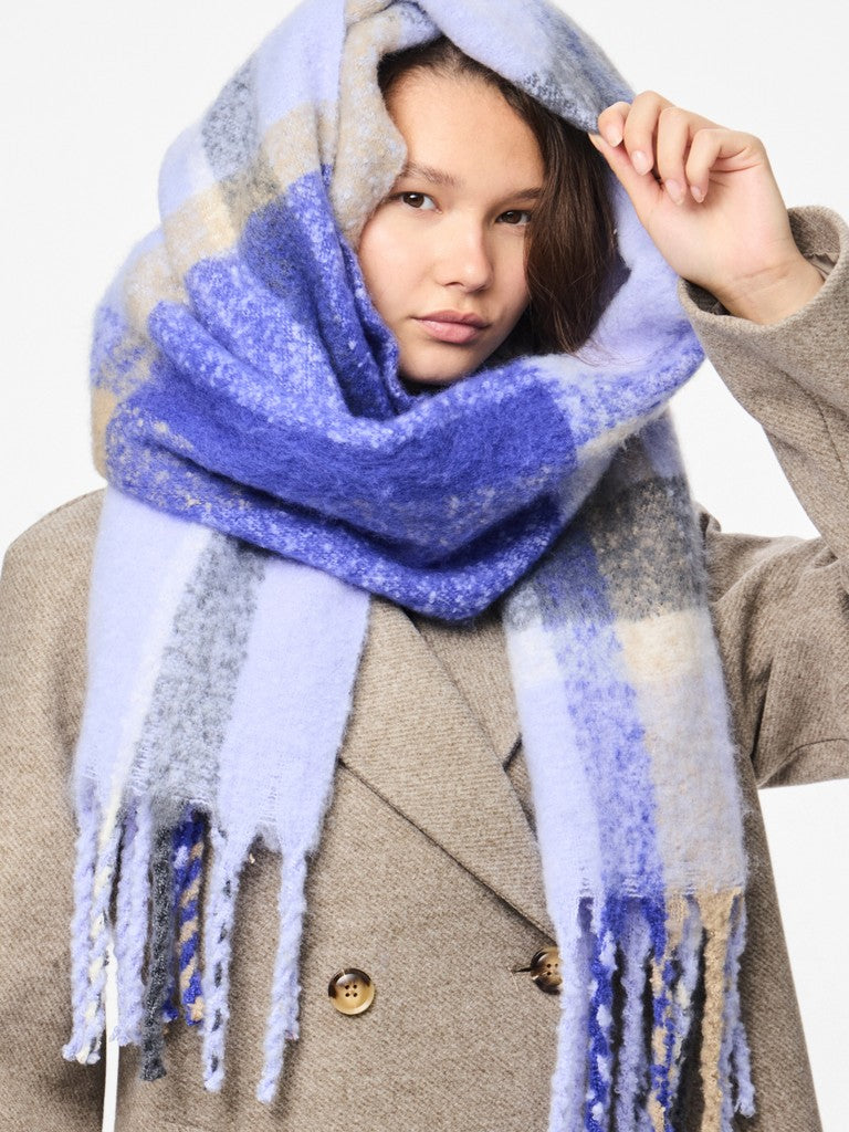 Person wearing a blue and gray plaid scarf with a neutral background