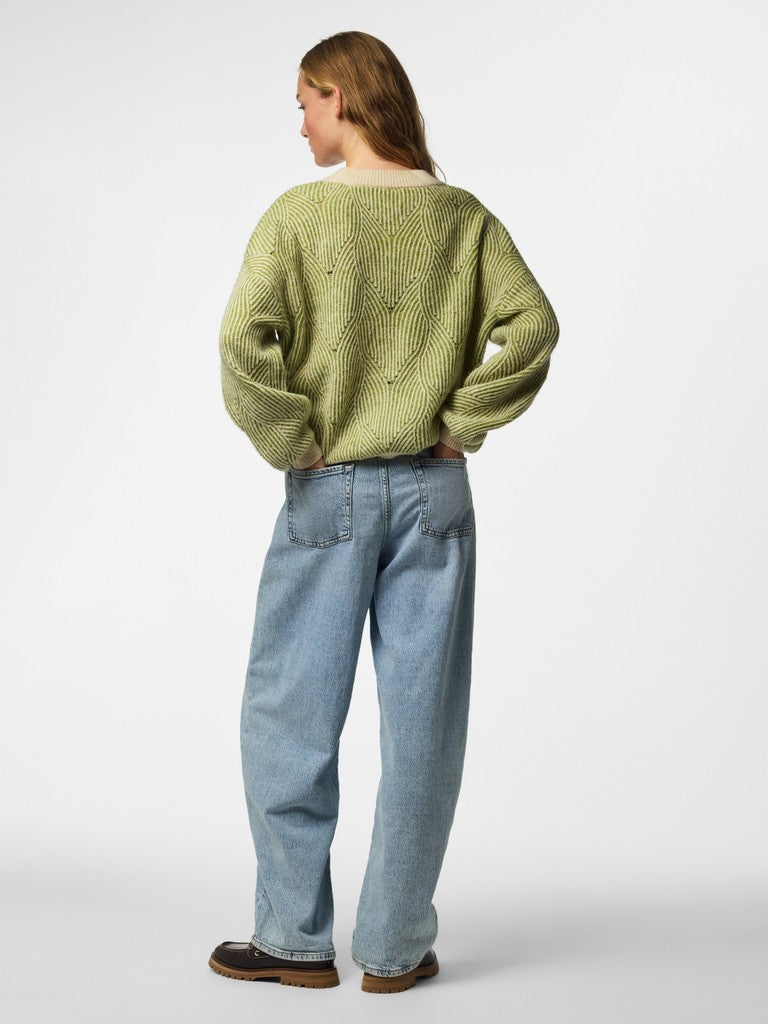 A model shown from the back wearing a light olive green knit sweater, light blue wide-leg jeans, and brown shoes, photographed against a neutral light gray studio background.