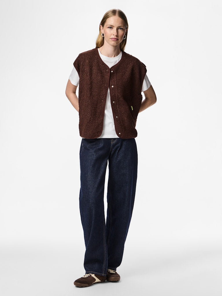 Person wearing a Pieces Katty Teddy Vest Chicory Coffee a white shirt with dark pants on a white background