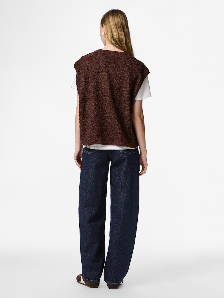 Person wearing a brown sleeveless top and dark blue jeans on a white background