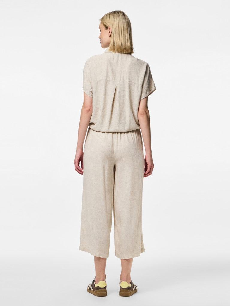 Woman wearing a beige top and wide-leg pants on a white background