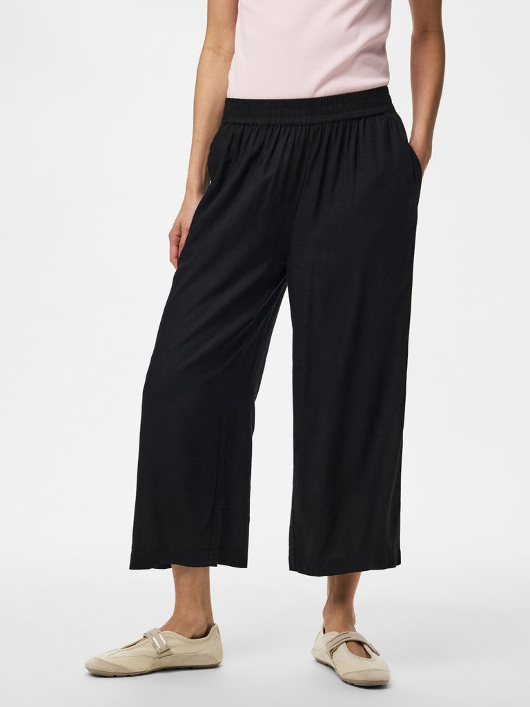 Person wearing black wide-leg pants and beige shoes on a white background