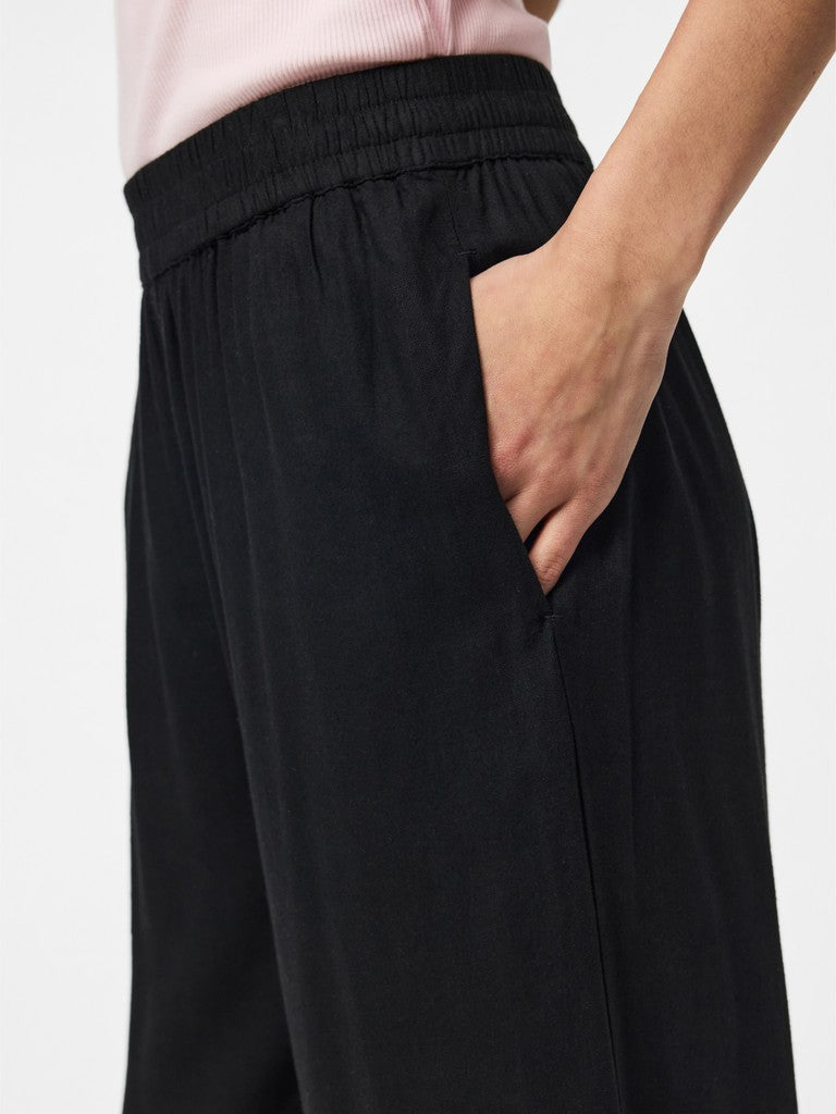 Person wearing black pants with a plain background