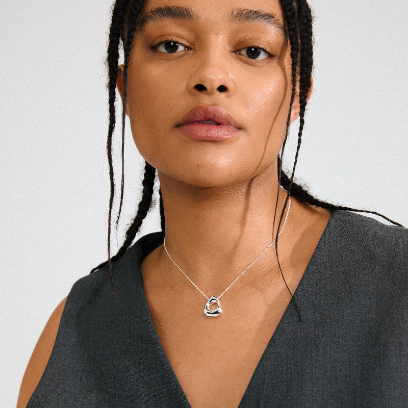 Woman wearing a Pilgrim Free Necklace Silver-platedwith a organic shaped pendant against a plain background