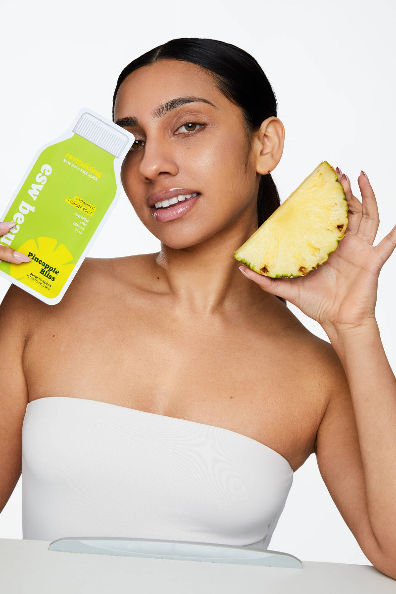 Woman holding a pineapple and a bottle of 'Easy Beauty' product on a white background