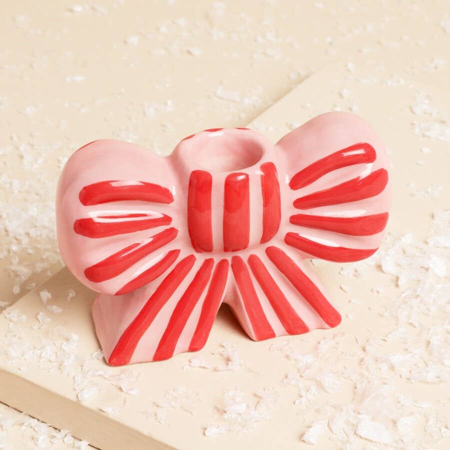 Pink and red bow-shaped object on a textured beige surface