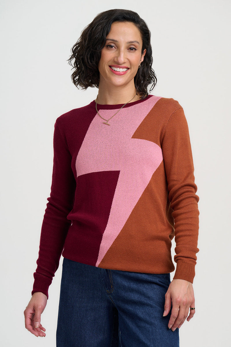 Woman wearing a color-blocked sweater with maroon, pink, and brown sections on a white background.