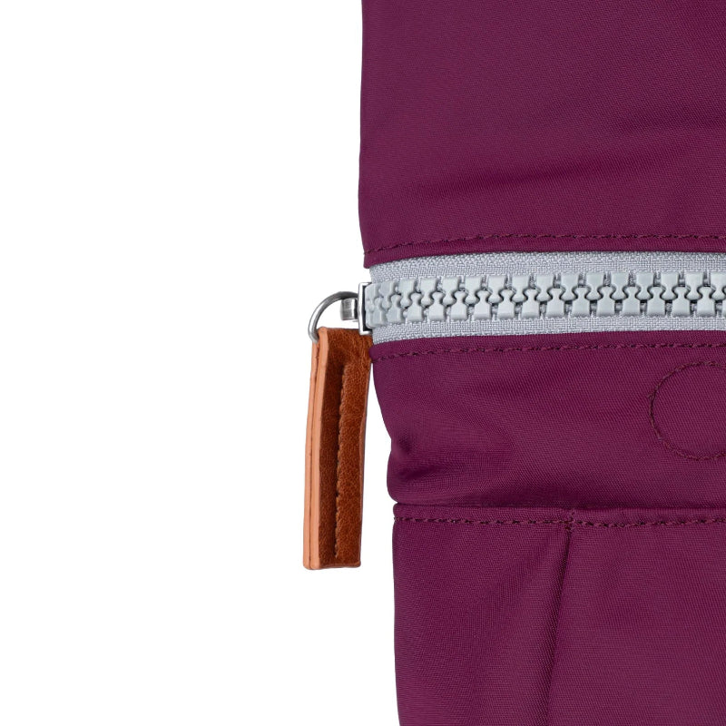Close-up of a purple jacket zipper with a brown pull tab on a white background