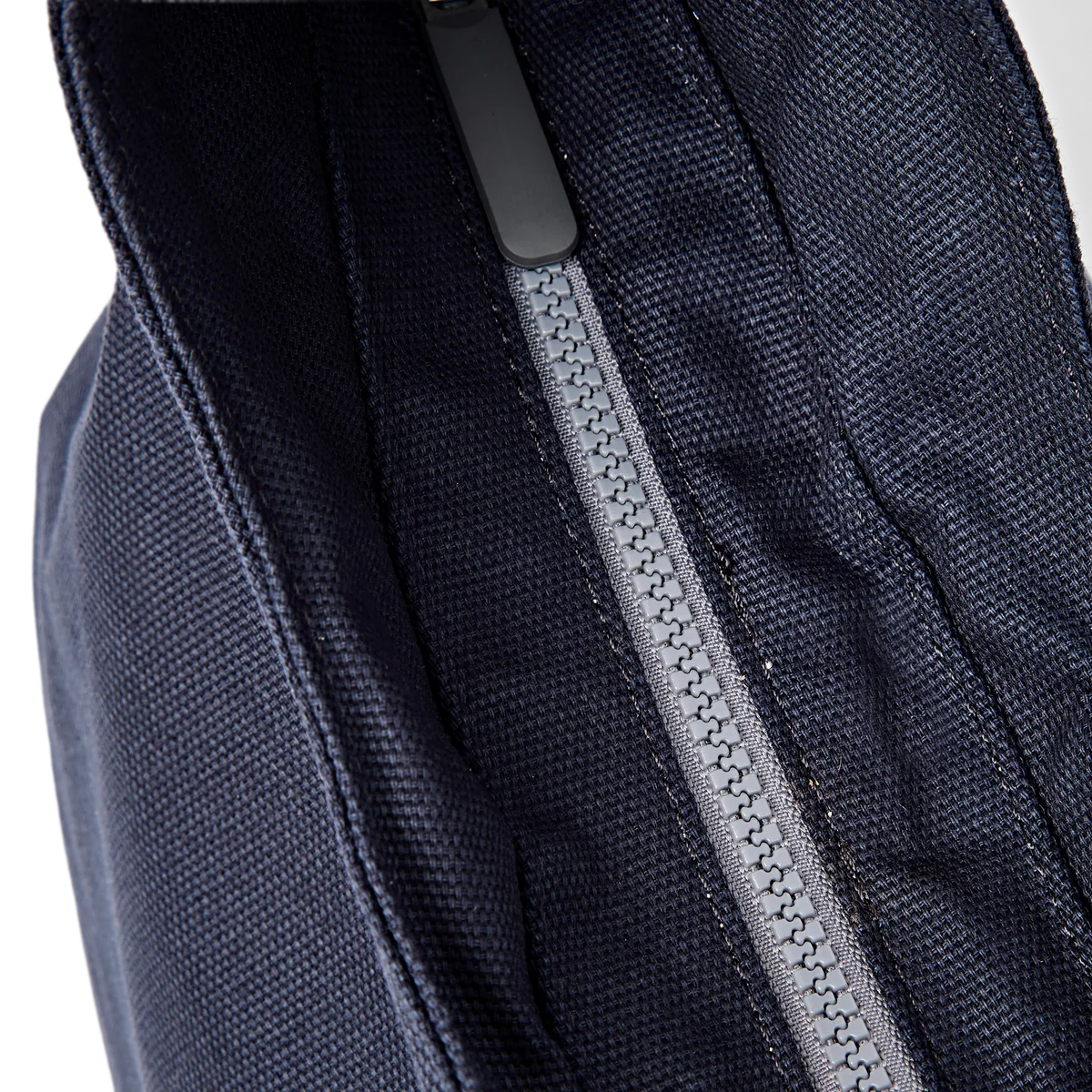 Close-up of a dark navy blue textured fabric bag with a gray zipper pull and a gray zipper track.