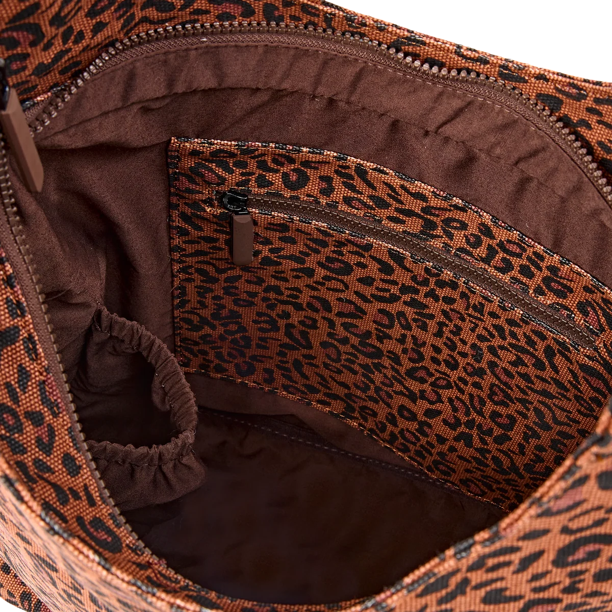 Close-up of the interior of a leopard-print handbag or tote, showing a brown and black patterned lining with a zippered pocket and elastic loop.