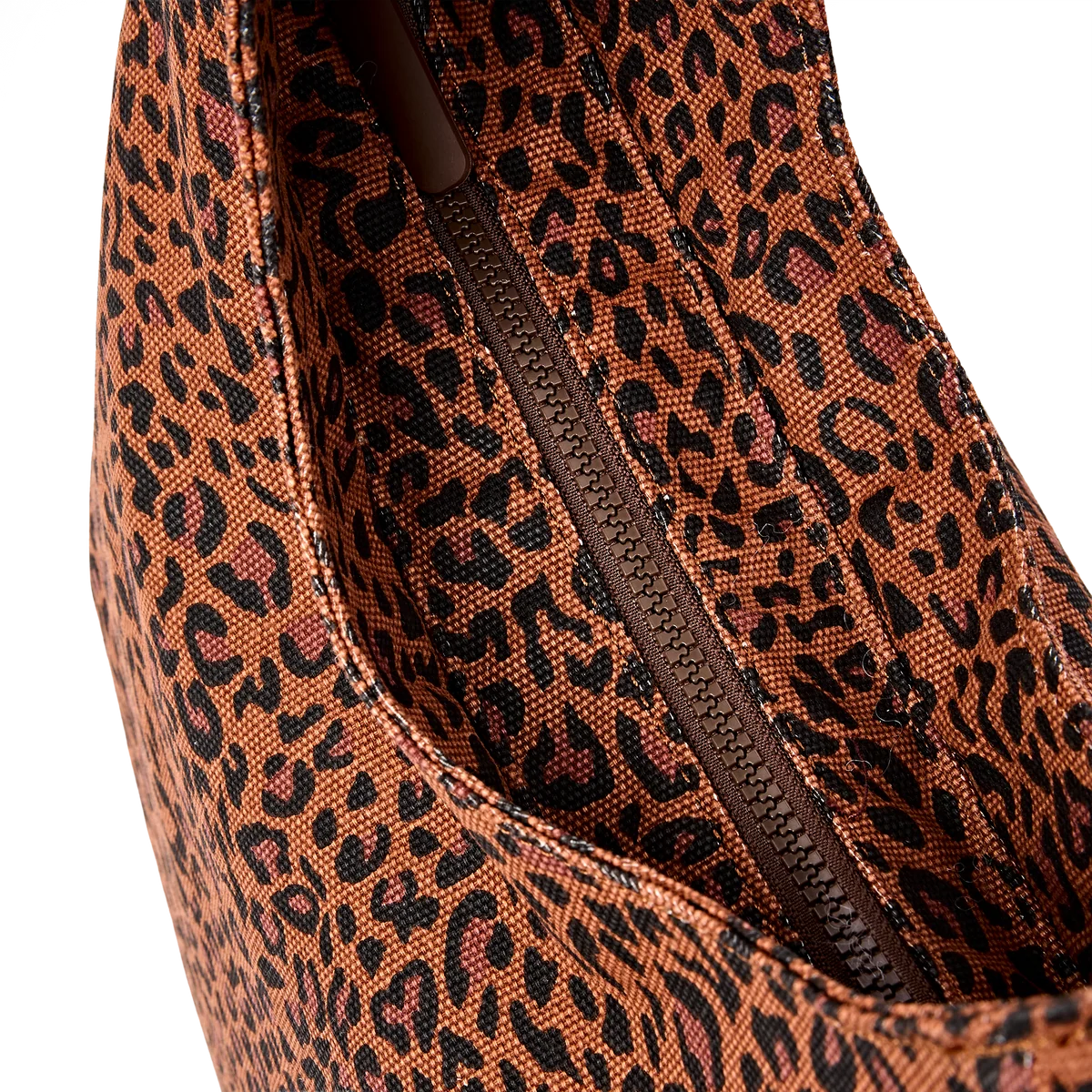 Close-up of a leopard print fabric bag interior with a brown zipper, showing the pattern and material texture against a white background.