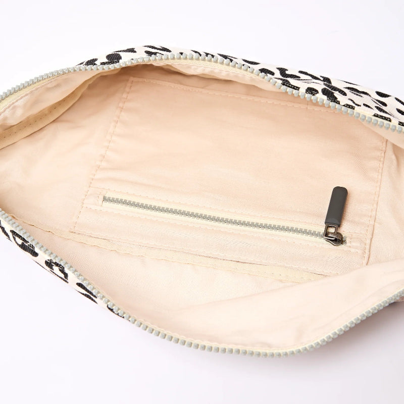 Close-up of a beige pouch with a black and white patterned zipper on a white background