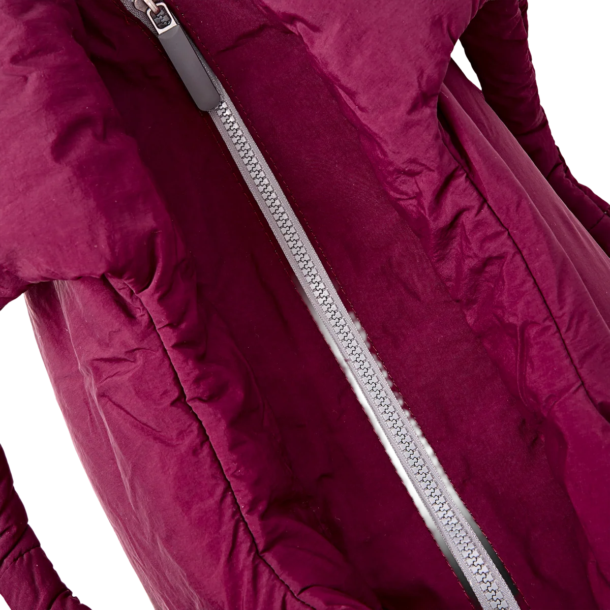 Close-up of a quilted puffer jacket in deep magenta with a prominent silver zipper running diagonally across the frame.
