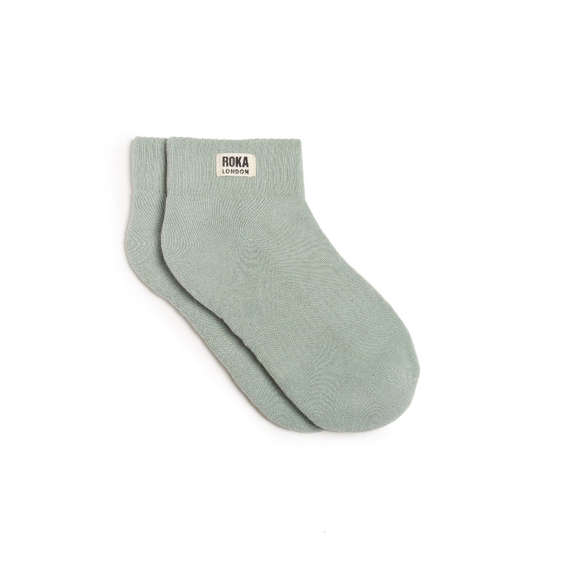 Pair of light green socks with 'ROKA LONDON' label on a white background