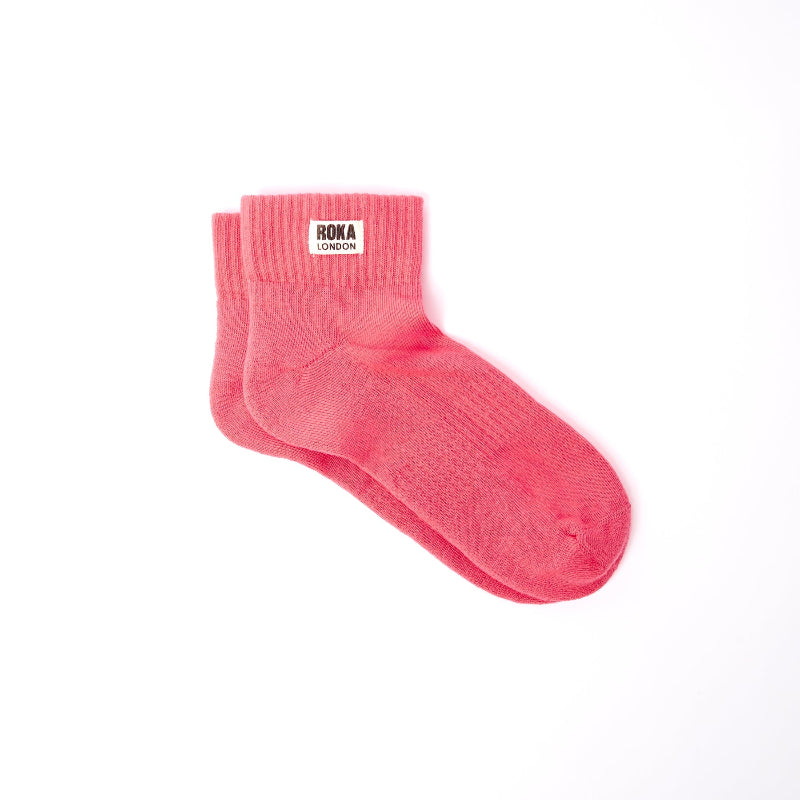 Pink sock with 'Roka London' label on a white background